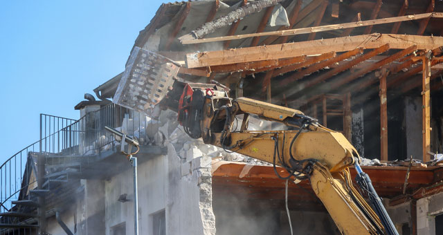 Excavator demolishing house